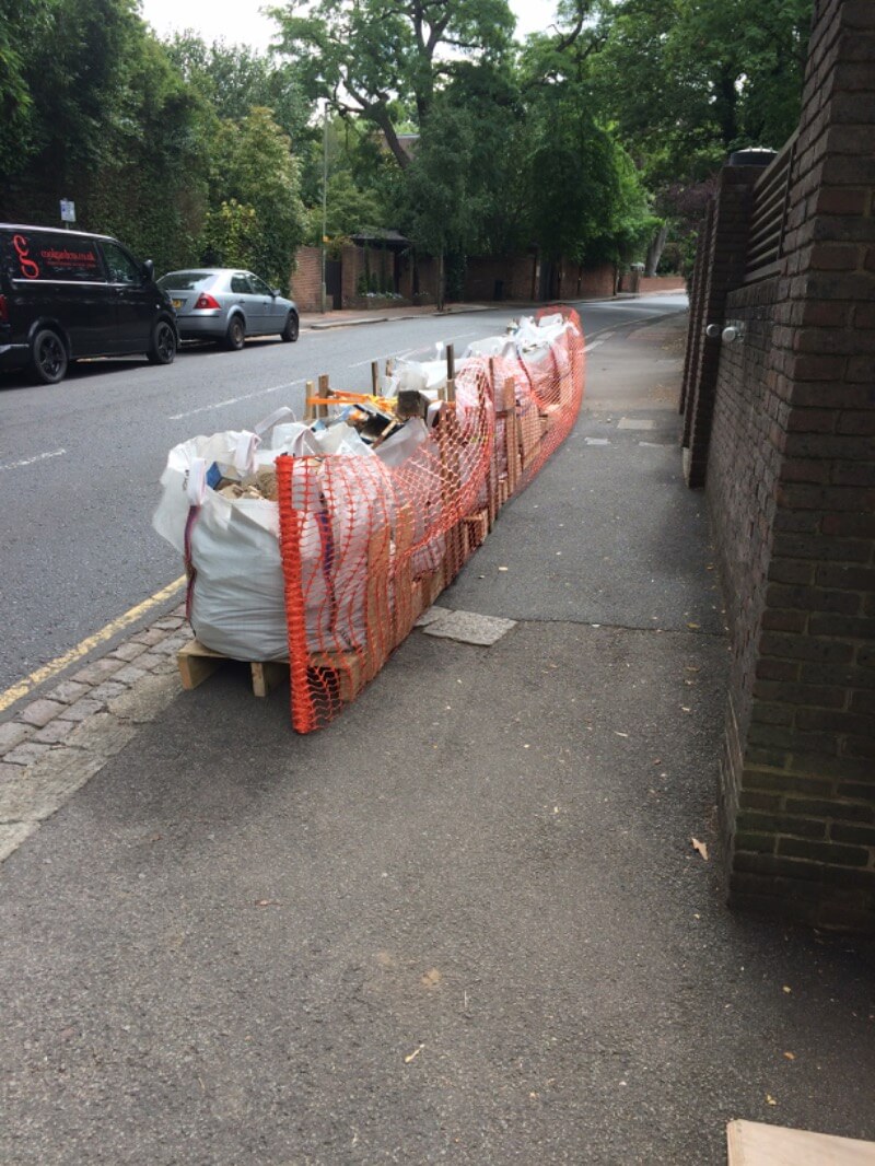 Some bags on construction materials sat on a pavement next to a road