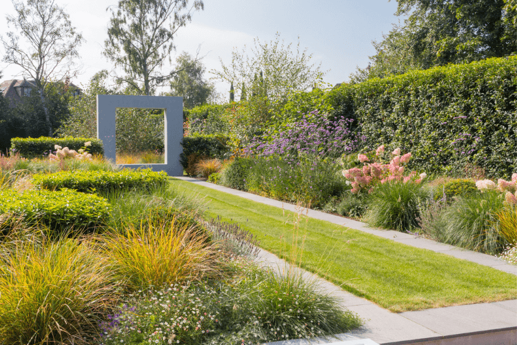 Contemporary garden with architectural planting, long lawn axis and sculptural concrete frame creating a modern focal point.