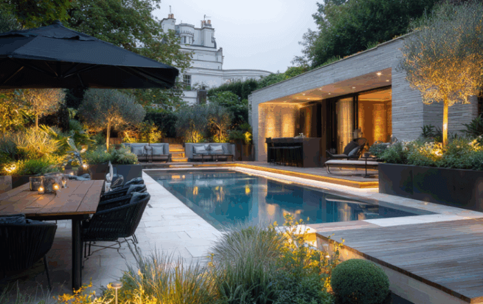 Contemporary luxury garden by CGLA with swimming pool, outdoor dining area and soft evening lighting highlighting structured planting.