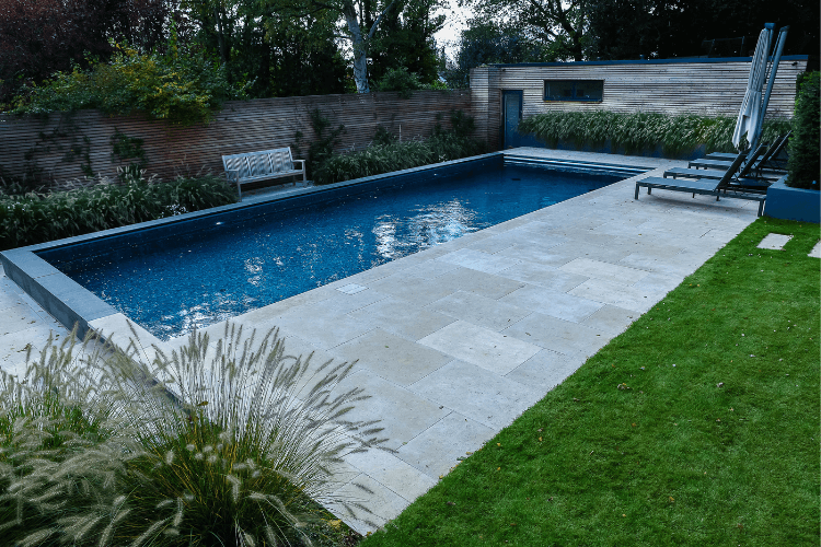 Modern lap swimming pool with stone paving, timber fencing and simple planting, designed for both leisure and fitness
